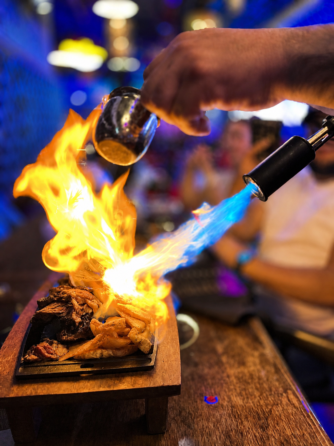 A dish being prepared with a flame at a table